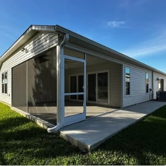 White-frame screen room with a screen door, opening onto a concrete patio