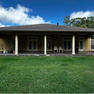 Screened rear porch on a home with an open lawn