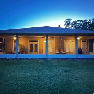 Covered and screened rear porch lit at dusk