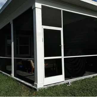White-frame screen room with a hinged screen door on a low-set home
