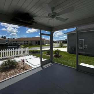 Inside a finished screen porch looking out across the yard, ceiling fan overhead